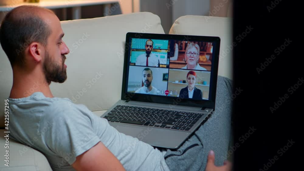 Poster over shoulder view of man in pajamas having online conversation with teammates working at online tec
