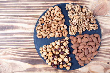 Various nuts sorted in glass bowl with honey bowl and honey dipper