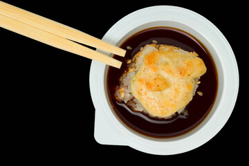 baked sushi roll with cream in soy sauce and sticks on a black background, top view
