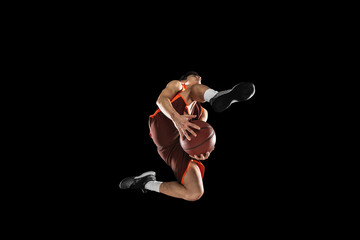 Young professional basketball player in action, motion isolated on black background, look from the...