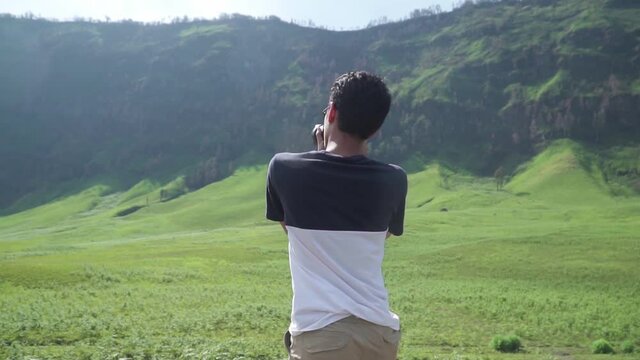 Young asian man taking a picture of beautiful mountains landscape in Bromo Mountain National Park, East Java, Indonesia