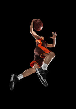 Young professional basketball player in action, motion isolated on black background, look from the bottom. Concept of sport, movement, energy and dynamic.