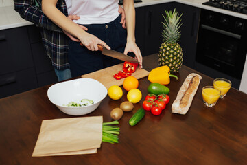 Cropped shot of husband hugging from behind wife while making salad.