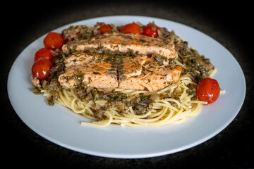 fresh cooking at home and ready to eat - rosted salmon with herbs and cerry tomatoes on spaghetti