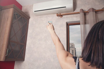 Female hand using remote controller for adjust Air conditioner.