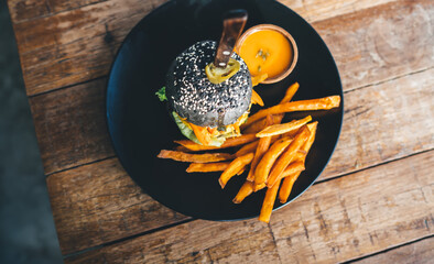 Delicious burger with french fries placed on wooden table