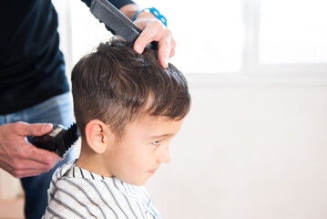 A little boy cutting his hair. Hairdresser cutting a child's hair