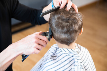 A little boy cutting his hair. Hairdresser cutting a child's hair