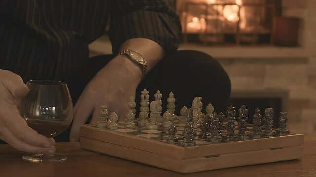 Game of Chess. Close Up of Hand Confident Businessman taking a glass of spirit.