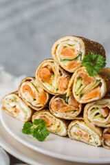 Traditional Russian pancakes with salmon, cucumber and curd cheese on a light background, close-up. Menu concept. Free place.