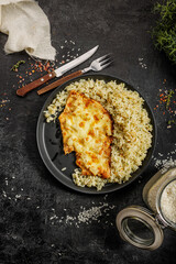Grilled hawaiian chicken with cheese, ananas and boiled rice served on a black plate