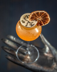 cocktail arancione con decorazione di fetta d'arancia disidratata secca, poggiato su mano di...