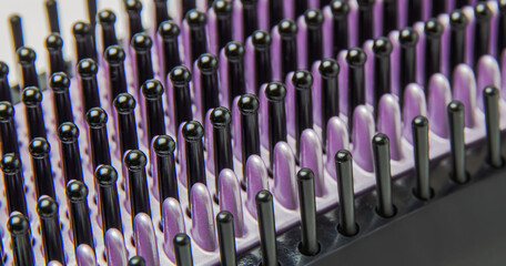 Black with purple bristles electric thermo hair straightening Brush. Macro photography