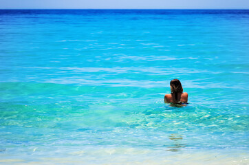 Rear view of young woman relaxin in turquoise colored sea