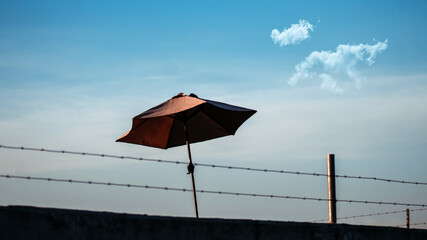 sombrilla detr&aacute;s de un muro con una reja 