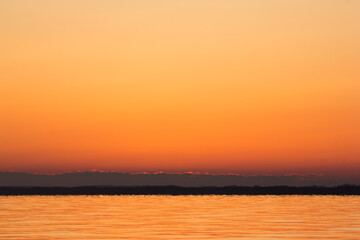 Obraz premium Sunrise at the river Drava in Croatia, Lake HE Dubrava, warm red black and yellow dramatic colors of sunset landscape silhouette with huge sun, photo taken in peaceful early morning