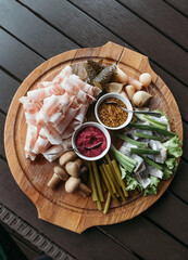 Russian traditional snack on wooden board. Tasty appetizer with pickled cucumber, mustard and lard.