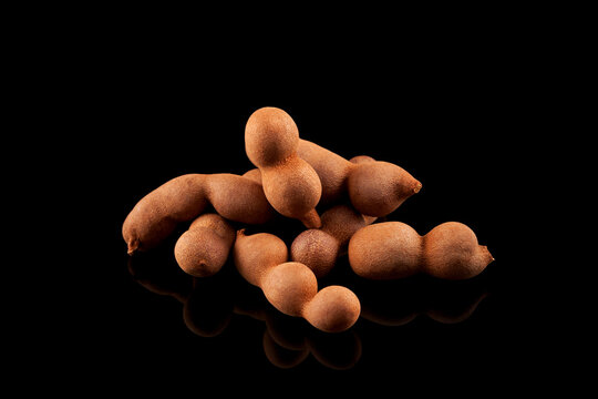 Tamarind (Tamarindus indica) is an edible fruit native to Tropical Africa. Fruit contains the sweet, pungent pulp that is used in cuisines around the world. Dark background, copy space