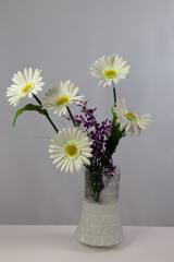 Bouquet of white artificial daisies. Which stands on the table in a vase.