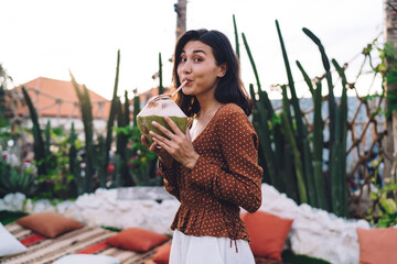 Cheerful young female sipping coconut water