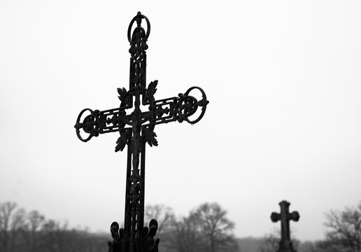 Old cemetery in rural France at autumn. Wet rusty cross with crucifix. Selective focus. Black and white photo.