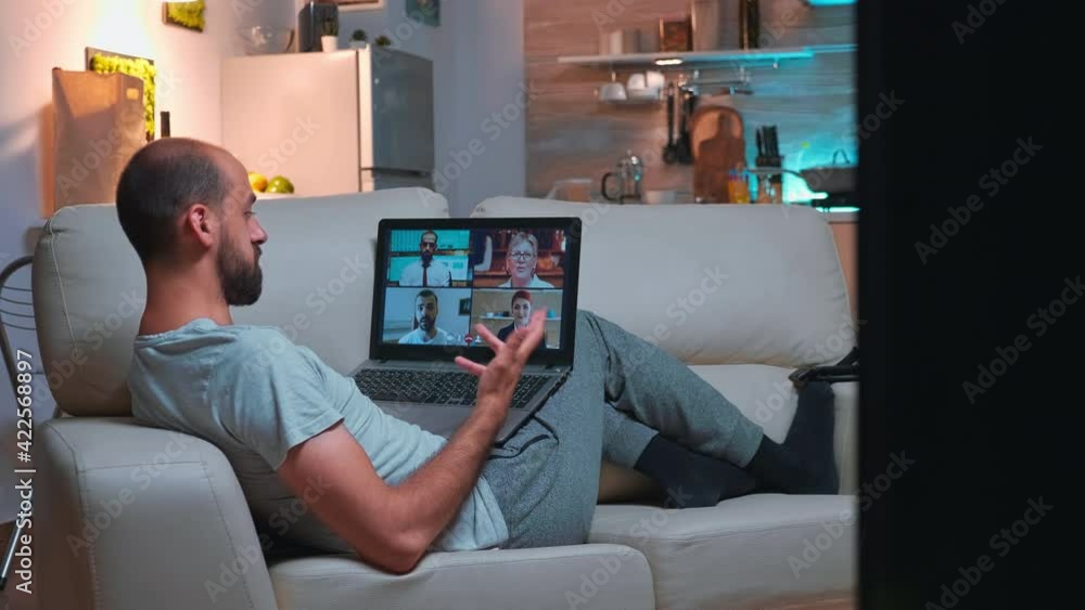 Aufkleber business man in pajams lying on sofa while chatting with friends during videocall meeting using lapt