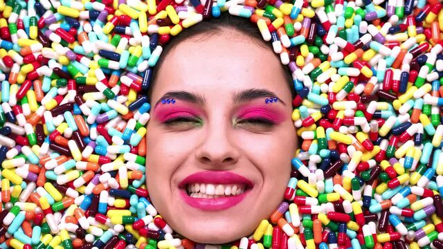 Artistic image of a beautiful woman sunk inside colored pills and capsules. 