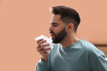 Young man suffering from runny nose indoors