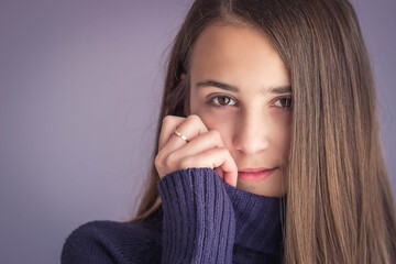 Portrait of a young brunette girl looking shy on purple background