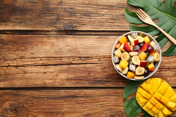 Delicious exotic fruit salad on wooden table, flat lay. Space for text