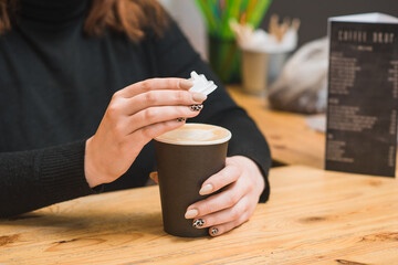 The hands of a female barista close the lid of a glass with coffee