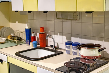 A kitchen table with electric hotplate, sink and equipment, retro style eastern europe in socialist era.