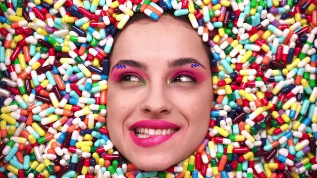 Artistic image of a beautiful woman sunk inside colored pills and capsules. 
