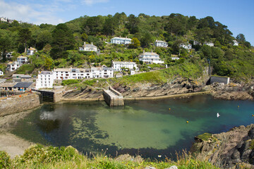 Fototapeta na wymiar Cornwall coast scene entrance to Polperro harbour UK with clear blue green sea 