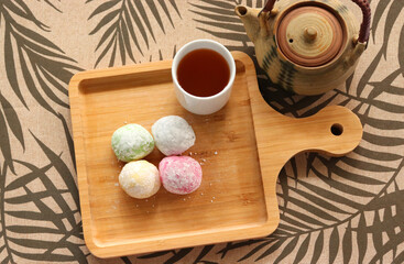 Daifuku Mochi and Green tea, put on the wooden tray. A teapot placed nearby. Top view photo.