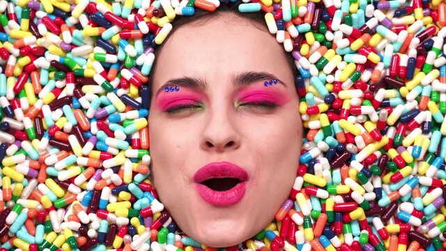 Artistic image of a beautiful woman sunk inside colored pills and capsules. 