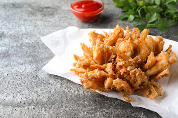 Fried blooming onion with dipping sauce served on grey table. Space for text