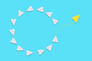 Business. A yellow paper airplane will fly out of the circle of white airplanes. Blue background. Flat lay. The concept of creativity and individuality