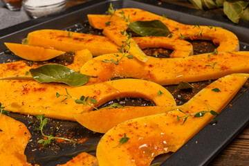 Many bright slices of pumpkin prepared for baking in the oven.