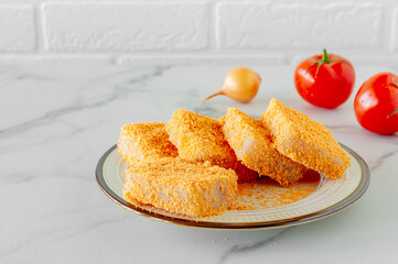 breaded fish patties on a plate prepared to cook