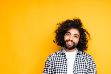 Happy african american young guy with beard smiling broadly while standing on yellow background