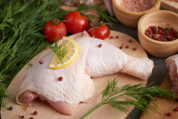 fresh chicken meat portions for cooking and barbecuing with stir fry with legs with skin viewed from above with fresh seasoning, Raw uncooked chicken leg on cutting board.