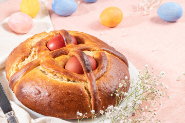 Portuguese traditional Easter cake. Folar with eggs on easter table. Blossom flowers and colorful painted eggs
