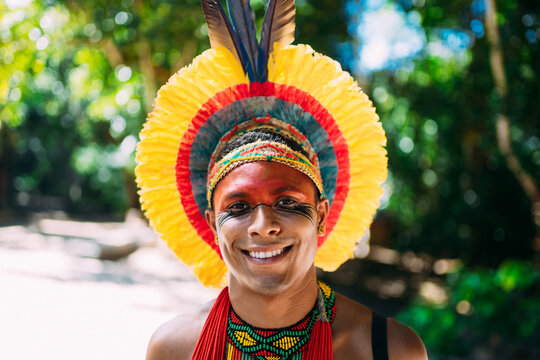 Indian from the Pataxó tribe with feather headdress looking at the camera. Indigenous man from Brazil, with traditional face paintings