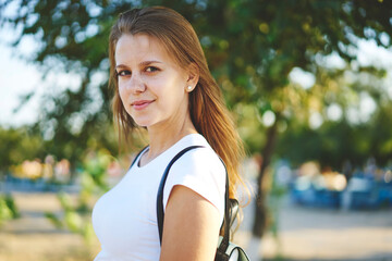 Close up portrait of teenage Caucasian woman with freckles resting on summer leisure enjoying sunny weather in park, young hipster girl 20s in casual wear posing during free time on weekend