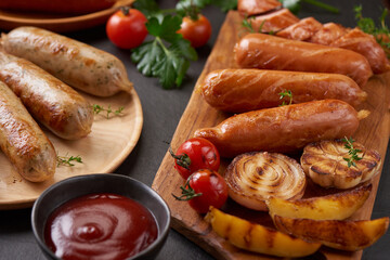 sausages and ingredients for cooking. Grilled sausage with the addition of herbs and and spices, vegetables, rosemary, thyme on the grill plate, Grilling food, bbq, barbecue, on stone table. Top view.