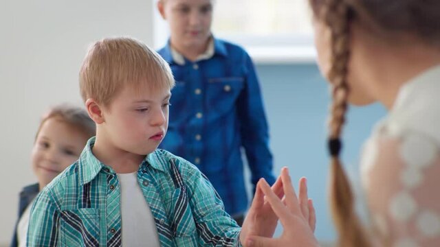male child with down syndrome holds hand to girl during lesson, development of disabled children