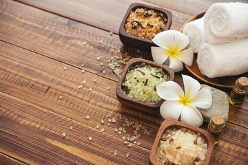 Sea salt, towels, aroma oil in bottles and flowers on vintage wooden background. Selective focus.