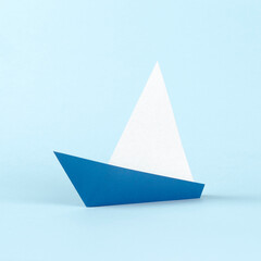 Origami white and blue paper sail boat on blue background