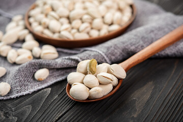 Pistachios in a wooden spoon. Wooden bowl with nut pistachios. on a wooden background, near a bag from burlap. Healthy food and snack, organic vegetarian food. (selective focus; close-up shot)